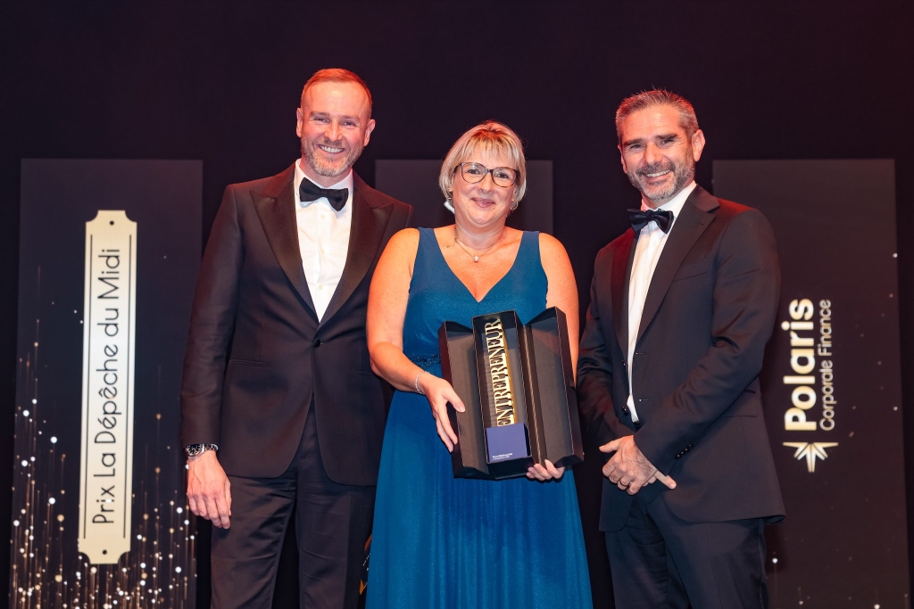 Trois personnes en smoking et robe de soirée sur scène lors de la cérémonie des Trophées de l'Économie, avec Sabine Tétré au centre tenant son prix de l'Entrepreneur de l'année décerné par La Dépêche du Midi et Polaris Corporate Finance.